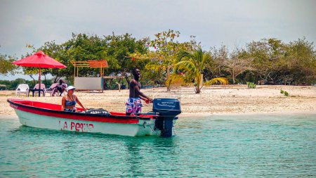 Foto de Cartagena de Indias, Bolvar, Colombia - 10 de abril de 2022 Hombre negro latino arrancando un motor de canoa con una mujer blanca a bordo - Imagen libre de derechos