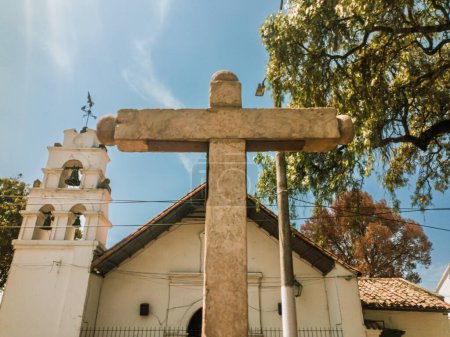 Denkmal des Steinkreuzes mit der San Bernardino-Kirche im Hintergrund in Bosa, Bogota - Kolumbien