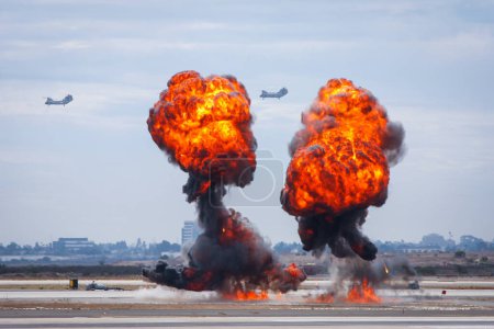 Téléchargez les photos : Explosion d'une bombe dans un aérodrome avec des hélicoptères de combat en arrière-plan dans les airs - en image libre de droit