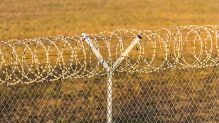 Zaun mit einer Rolle Stacheldraht an einer internationalen Grenze