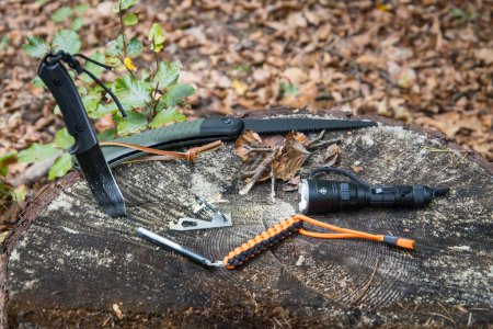 Several survival and bushcraft tools on a tree stump