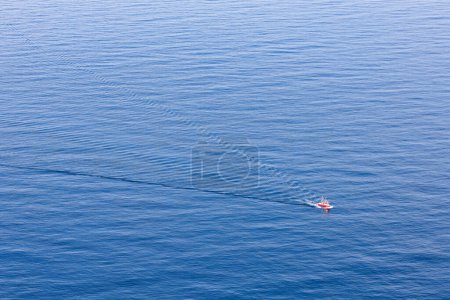 Barco de pesca en el océano azul ancho con el mar tranquilo