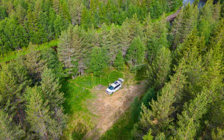 Luftaufnahme eines wilden Campingplatzes mit einem Wohnmobil, umgeben von Bäumen und Natur