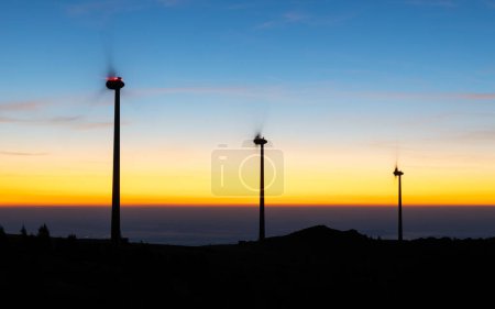 Groupe de moulins à vent pour la production d'électricité sur une crête montagneuse avant le lever du soleil