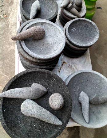 Téléchargez les photos : Vue rapprochée de l'outil traditionnel, à savoir un mortier en pierre, est utilisé pour pilonner la sauce chili et un mortier en pierre pour pilonner les épices dans les boutiques de souvenirs en Indonésie. Cobek. Outils de cuisine. - en image libre de droit