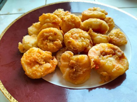 Harina de camarones fritos es un plato de camarones que se mezcla con harina y huevos, luego se fríe en aceite caliente. Servido en un plato rojo. Enfoque selectivo.