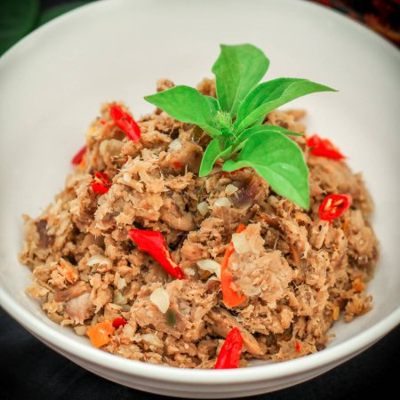Würziger zerfetzter Thunfisch ist eine indonesische Speise. Es besteht aus geräuchertem Fisch, Chilischoten, Gewürzen und Kräutern. Weißer Hintergrund. Selektiver Fokus.