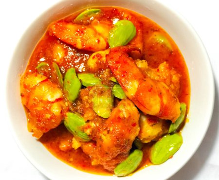 Selective focus. Chili prawns or Sambal Udang with petai or pete in white plate on white background. Indonesia cuisine food. 