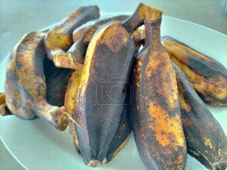 Several boiled Saba bananas are placed on white plate. Asians like to eat boiled bananas with hot beverages for breakfast.