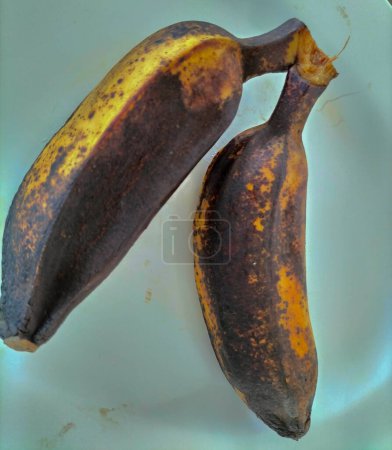 Several boiled Saba bananas are placed on white plate. Asians like to eat boiled bananas with hot beverages for breakfast.