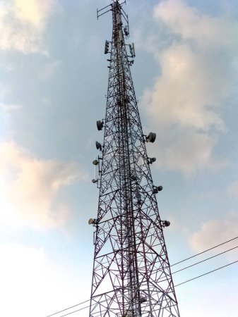 Closeup. Upper view of communication pole with the clouds fill the blue sky background.