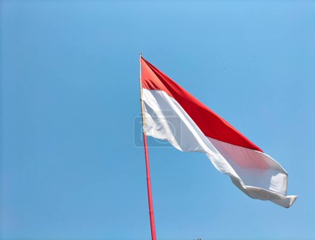 The red and white flag flutters against the background of blue sky. Selective focus.
