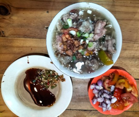 Vue rapprochée de la soupe d'agneau râpé servie avec des tomates tranchées, des oignons verts et des oignons frits. Indonésie nourriture. Délicieuse nourriture.