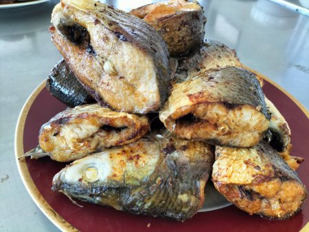 Milkfish frito, frito seco con condimento de cúrcuma, como plato casero indonesio. Servido en un plato. Enfoque selectivo