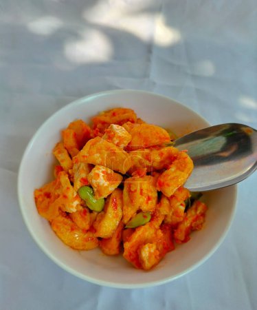 Closeup view of one serving of balado fried tofu, served on white bowl for lunch. White background.