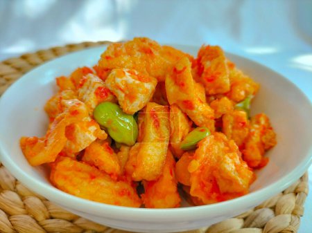 Closeup view of one serving of balado fried tofu, served on white bowl for lunch. White background.