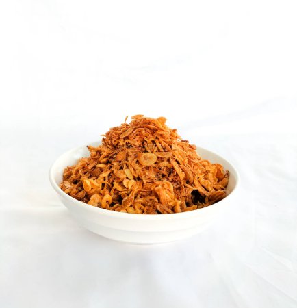 Frittierte Schalotten zum Garnieren in einer weißen Schüssel. Diese gebratenen Schalotten sind ein Gewürz, das häufig als Aroma auf verschiedenen indonesischen Gerichten verwendet wird. Rote Zwiebel. Selektiver Fokus.