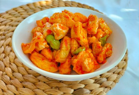 Selective focus. Tahu Balado or spicy seasoned tofu is Indonesian food made from fried tofu prepared with spices : shallots, garlic, large red chilies, brown and white sugar.Tahu Balado served on bowl