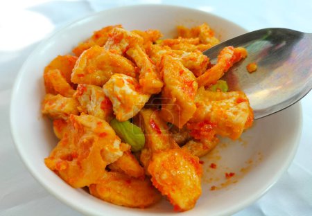 Selective focus. Tahu Balado or spicy seasoned tofu is Indonesian food made from fried tofu prepared with spices : shallots, garlic, large red chilies, brown and white sugar.Tahu Balado served on bowl