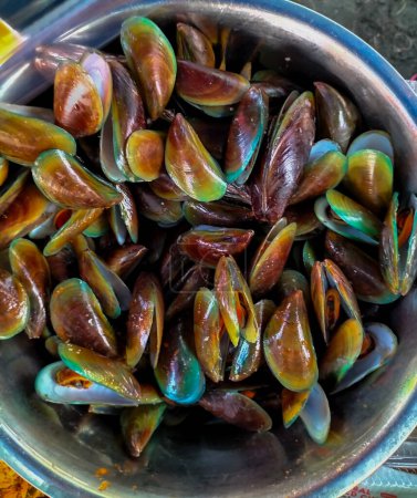 Foto de Selective focus. Mussels in spicy sauce on a stainless steel bowl on a wooden background horizontal. Yummy seafood. - Imagen libre de derechos