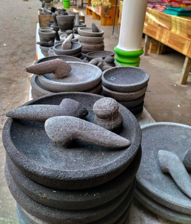 Closeup view of traditional tool, namely a mortar made of stone, is used to pound chili sauce and a stone mortar for pounding spices in souvenir shops in Indonesia. Cobek. Kitchen tools.