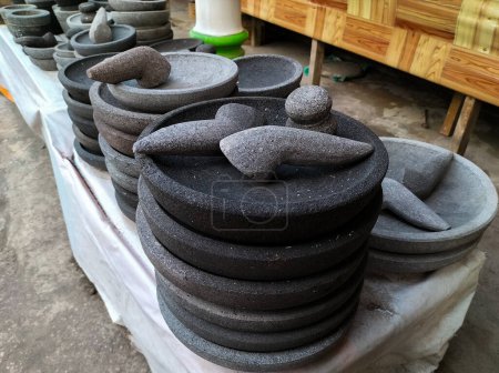 Closeup view of traditional tool, namely a mortar made of stone, is used to pound chili sauce and a stone mortar for pounding spices in souvenir shops in Indonesia. Cobek. Kitchen tools.