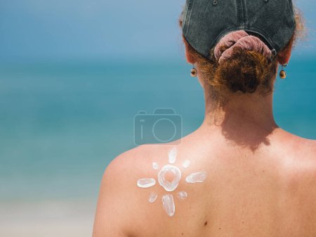 Creative view of a woman's back with sunscreen applied in a sun pattern, promoting skin protection at the beach