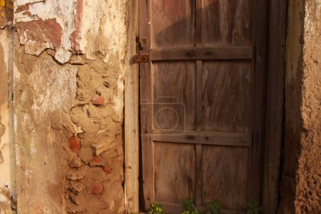 Téléchargez les photos : Une porte en bois altérée avec peinture pelante est installée dans un mur de briques rustique - en image libre de droit