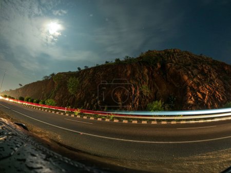 Téléchargez les photos : A long exposure photograph of a winding mountain road snaking its way up a verdant mountainside - en image libre de droit
