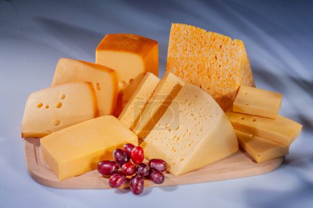 Käse und verschiedene Käsekompositionen mit Früchten. Hartkäse mit unterschiedlichen Texturen und Farben. Verschiedene Hartkäsesorten. Kleine Käsestücke mit Früchten.