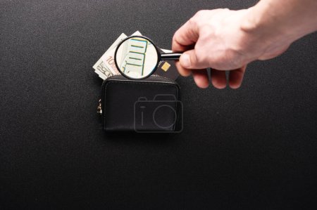 Foto de Checking dollars under a magnifying glass. Search for watermarks on banknotes. Authenticity of money. Magnifying glass and money in a wallet. - Imagen libre de derechos
