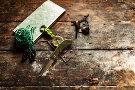 Knife and compass on the table. Knife and tourist items on the table. View from above.