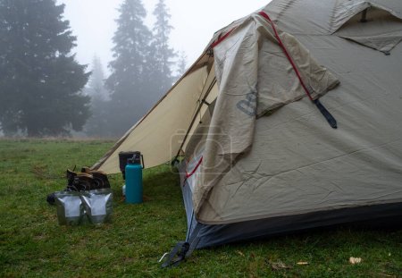 Téléchargez les photos : Tente touristique dans la forêt. Cuisine touristique et cuisinière à gaz près de la tente. Tourisme et gastronomie. Matin au camping. Brouillard dans la forêt. - en image libre de droit