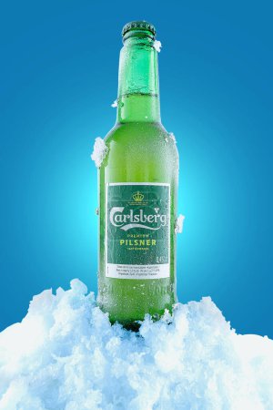 Téléchargez les photos : Kiev, Ukraine - 2 juillet 2022 : bouteille de bière Calsberg. Bière réfrigérée avec condensat et glace. Fond bleu. - en image libre de droit