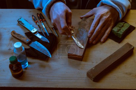 Foto de Antiguo cuchillo oxidado y piedra de afilar Restauración del cuchillo en el taller. Varios cuchillos viejos. Vista frontal. - Imagen libre de derechos