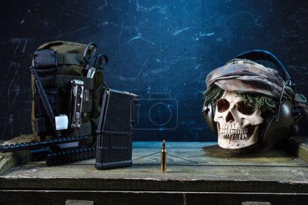 Photo for Military composition with a bullet and a skull. Machine gun bullet and military equipment. Skull and military headphones. Front view. - Royalty Free Image