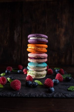 French cookies macarons and berries. Multi-colored cookies and berries. Fruit cookies. Vertical frame.