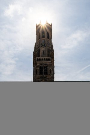 Photo for Beautiful view on the Belfry of Bruges under a blue sky during a sunny day. Backlight on the tower with a large flair on the sun. Point of interest of Bruges. Photography with nobody. - Royalty Free Image