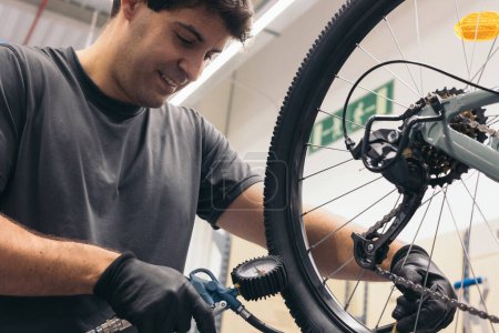 Foto de Mecánico caucásico comprobando la presión de las ruedas de bicicleta con compresor en taller - Imagen libre de derechos