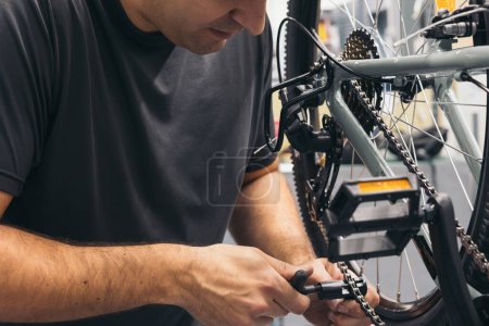 Photo for Closeup anonymous mechanic repairing bike chain with tool in workshop - Royalty Free Image