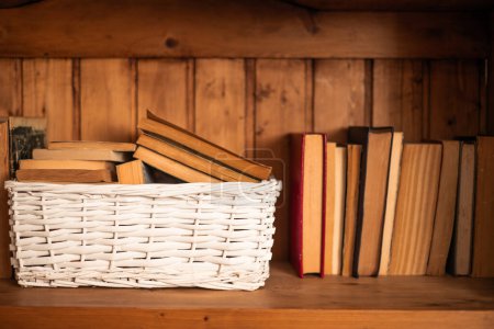 old books kept in a white wicker basket on the library bookcase