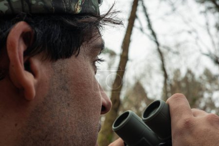 In this captivating close-up, a forest ranger stands as the guardian of the woods, attentively scanning with binoculars. His piercing gaze penetrates through the forest canopy, remaining ever vigilant to detect any signs of danger or intrusion. As a 