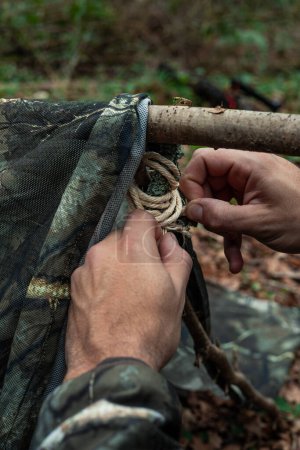 closeup In this evocative image, the skilled hands of an adventurer delve into the task of tying a knot in a rope amidst the serene beauty of nature. Every twist and pull of the rope reveals the adventurer's skill and determination to construct their