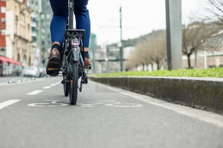copyspace Gros plan d'un homme d'affaires en tenue formelle pédalant son vélo électrique le long d'une piste cyclable urbaine, incarnant un mode de vie respectueux de l'environnement et actif au milieu du paysage urbain