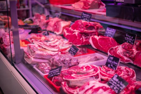 This closeup image showcases a variety of fresh meats displayed on the glass counter of a butcher shop. From beef to pork and lamb, the assortment offers a wide selection of choices for meat enthusiasts
