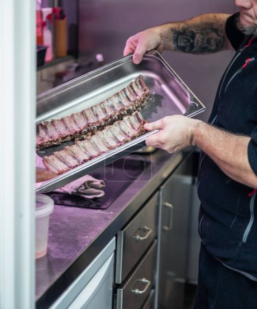 a closeup of a cook presenting a tray of freshly baked pork ribs. The succulent and tender ribs are a testament to the cook's skill and expertise in preparing mouthwatering dishes