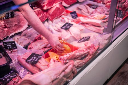 closeup of a butcher's hand selecting a chicken breast from the butcher shop counter. The scene highlights personalized attention and the quality of products offered at the butcher shop, promoting a positive experience for customers