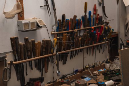 organized chaos of a carpentry workshop in this image showcasing a variety of tools hanging on the wall. From screwdrivers and tape measures to hammers and files, each tool tells a story of craftsmanship and meticulous attention to detail. The vibran