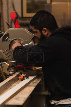 Foto de Primer plano carpintero latino repara una sierra circular eléctrica profesional en su taller de carpintería. Esta escena captura la meticulosa atención al detalle y la destreza artesanal esencial para mantener las herramientas de carpintería, reflejando el orgullo y - Imagen libre de derechos