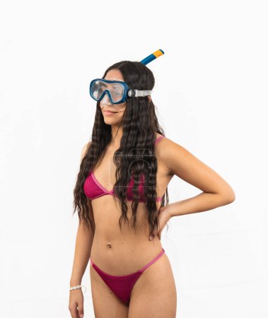 Adventurous Latin woman in bikini wears snorkel gear, including goggles and a snorkel tube, ready for an exciting day of snorkeling on a summer beach on white background